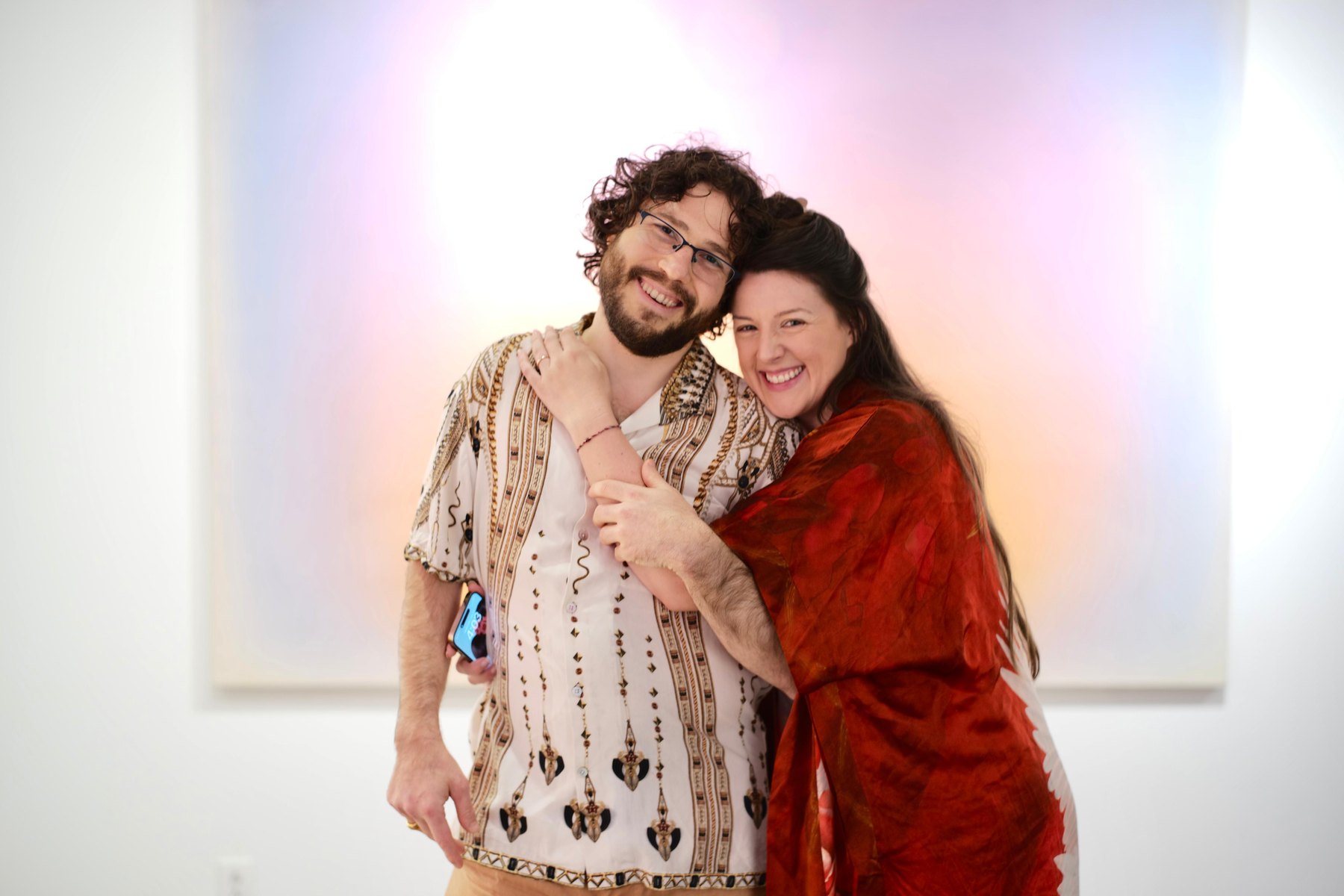 Kayla Rose Bergen and Vaughn Bergen together in a gallery, in front of a large luminous field painting.
